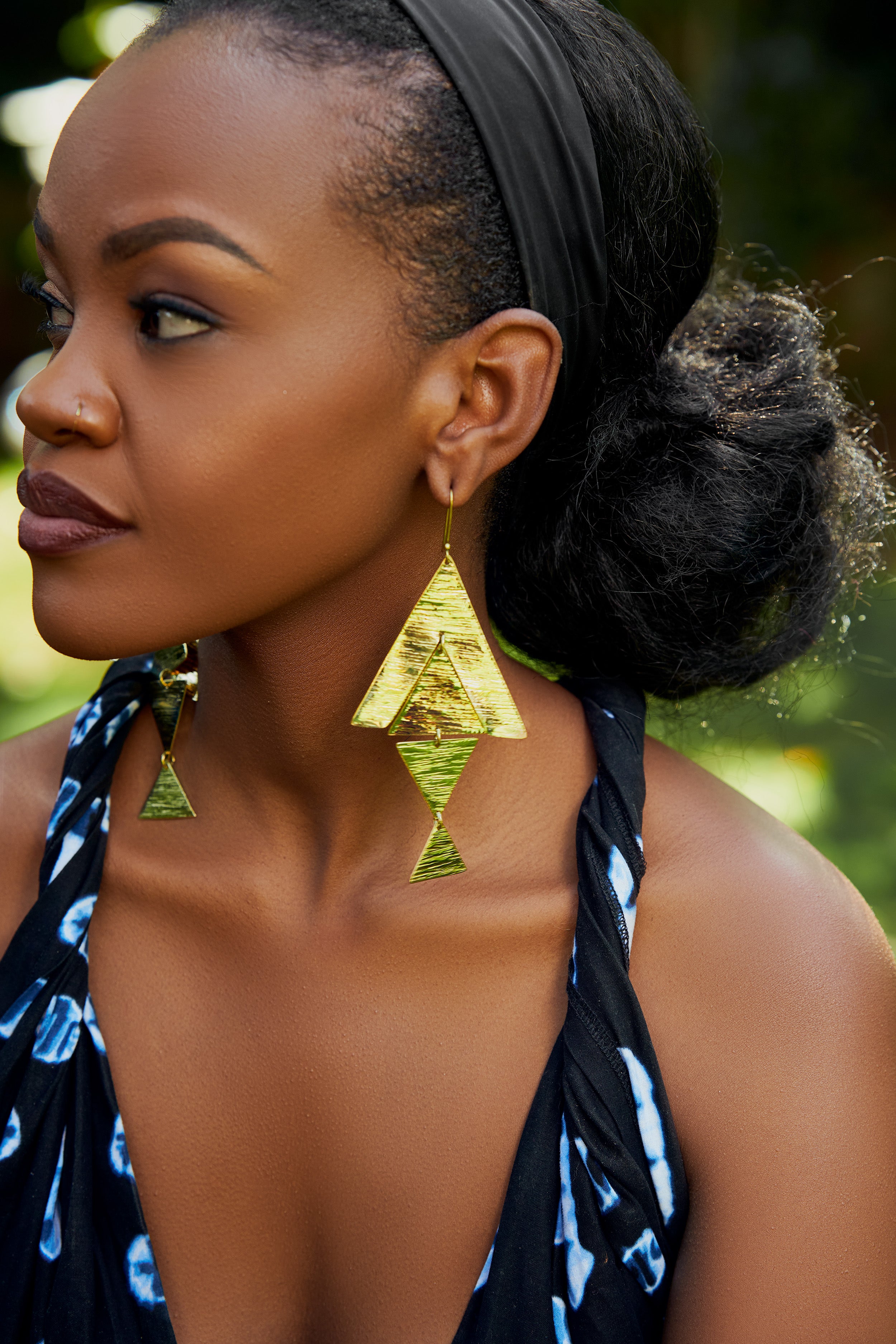 Close-up of a model wearing large, gold, triangular dangle earrings