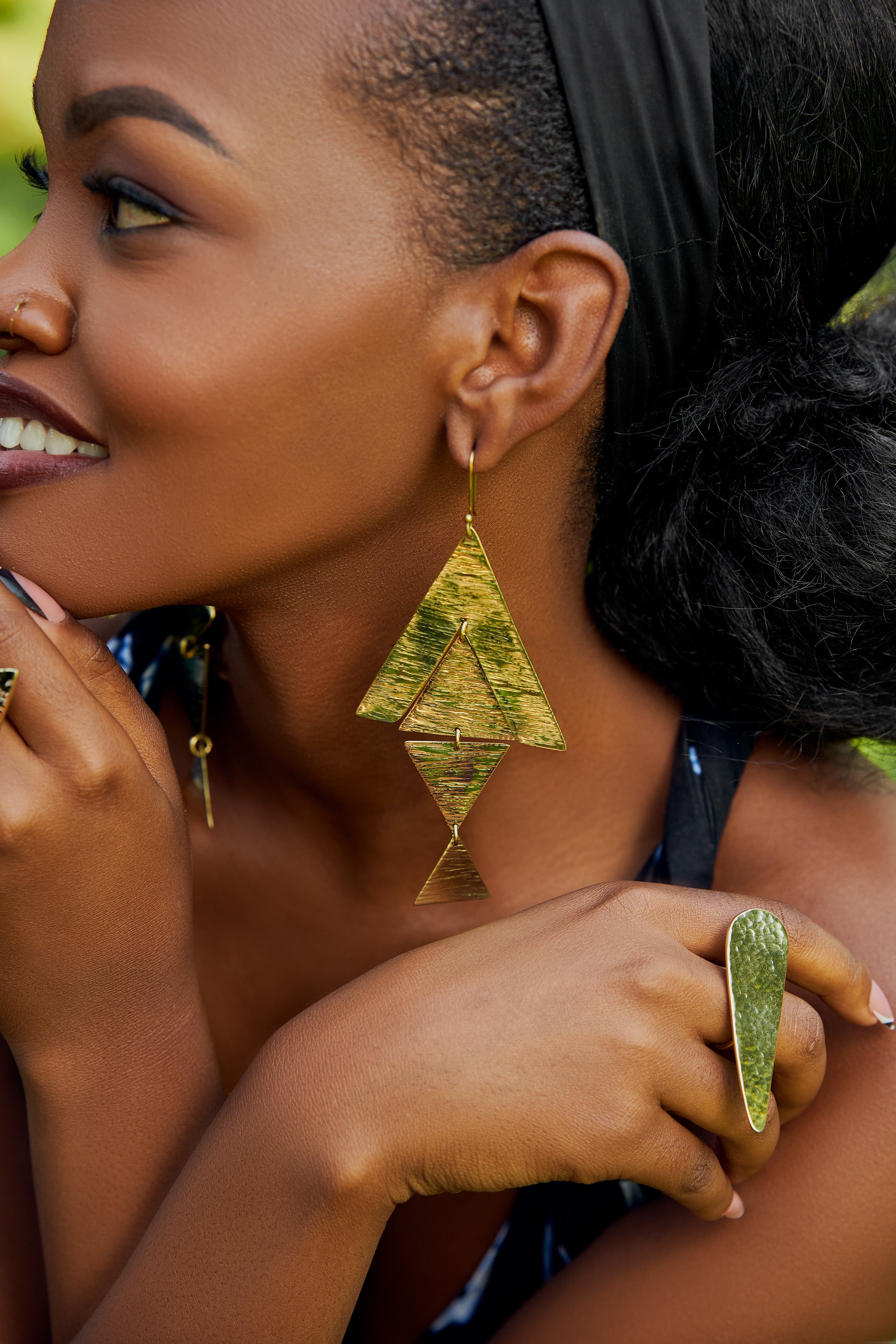 Close-up of a model wearing large, gold, triangular dangle earrings