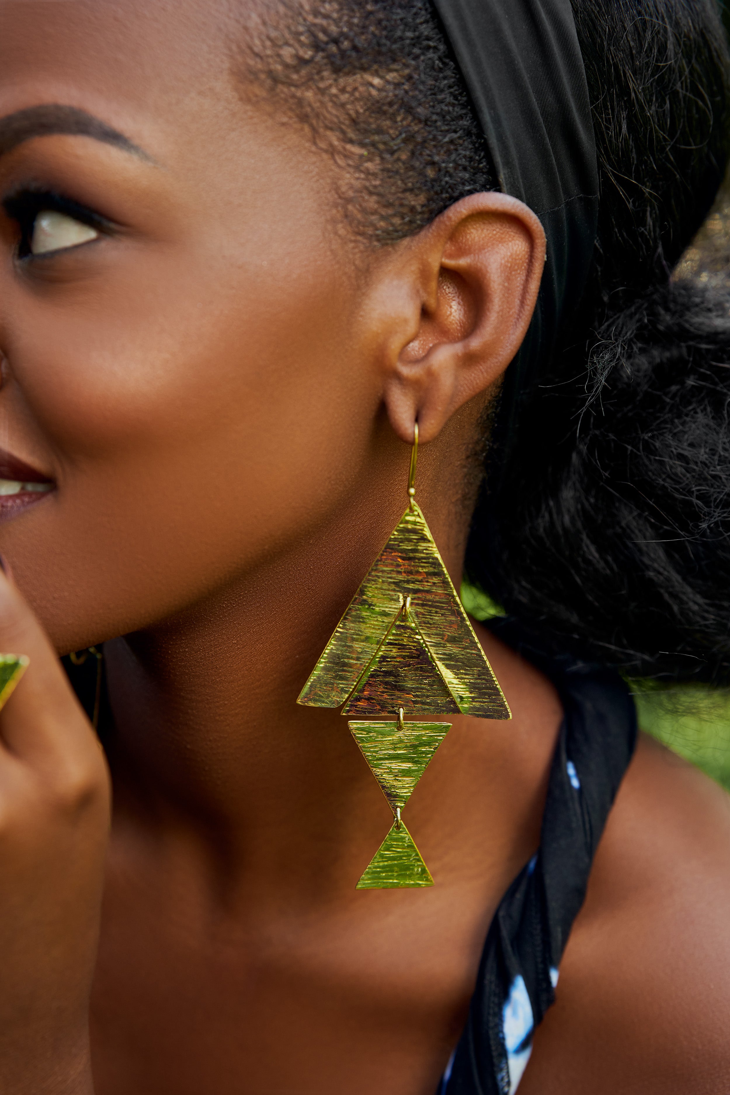 Close-up of a model wearing large, gold, triangular dangle earrings